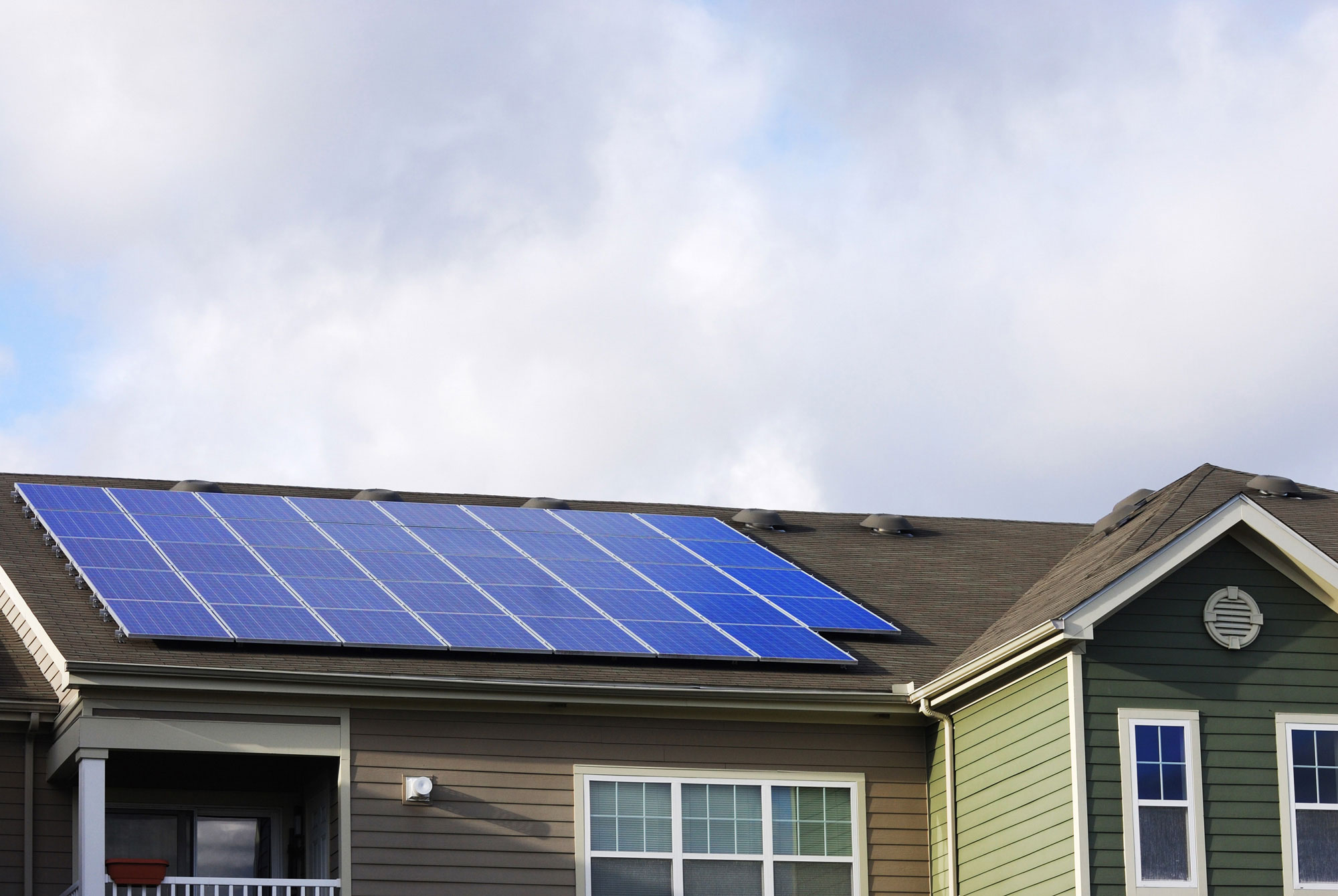 solar panels on roof of green sided house 